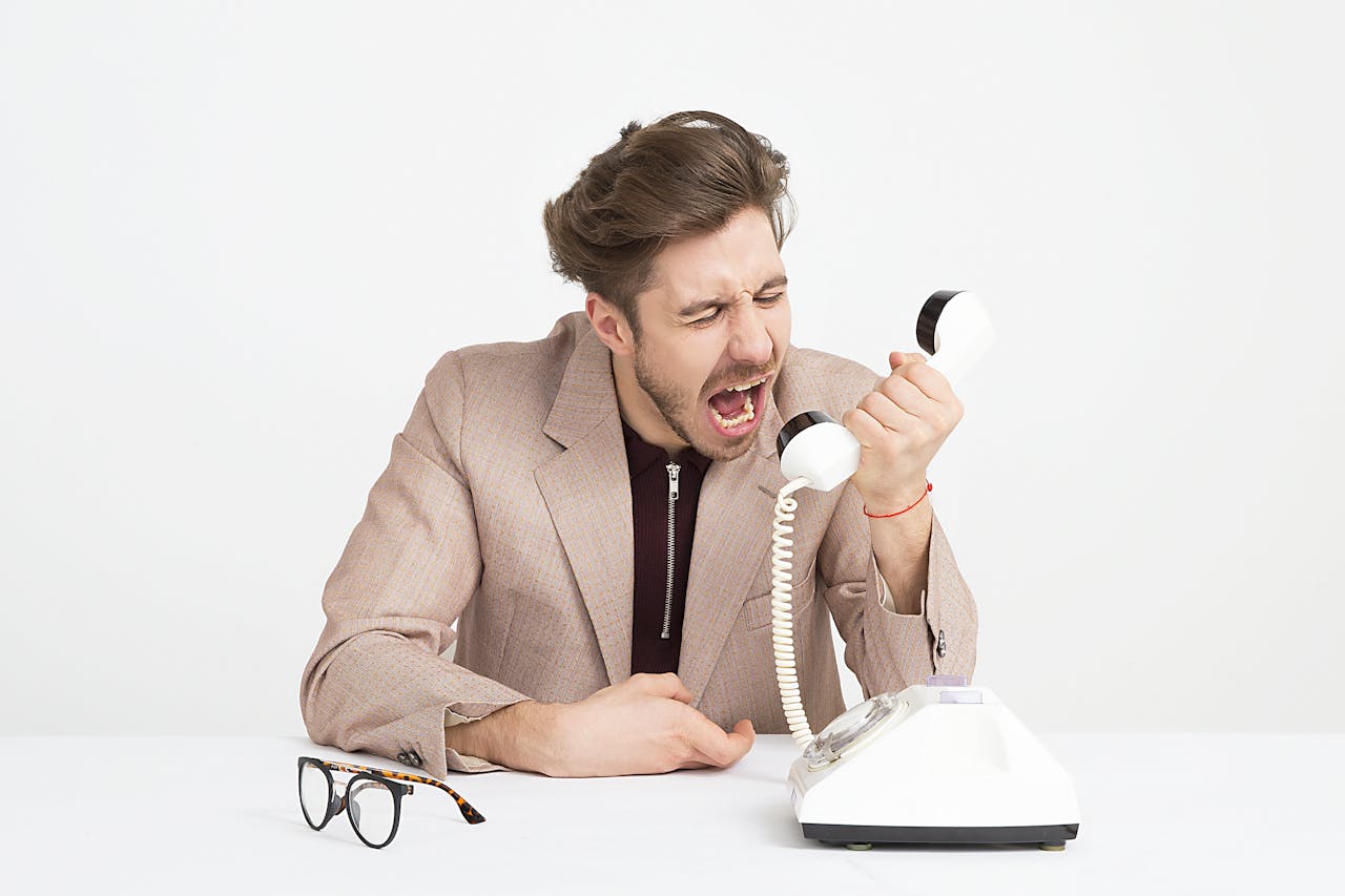 A stock photo of a man yelling into a phone handset